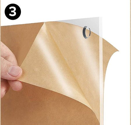 Hands peeling the brown protective film off a clear acrylic panel