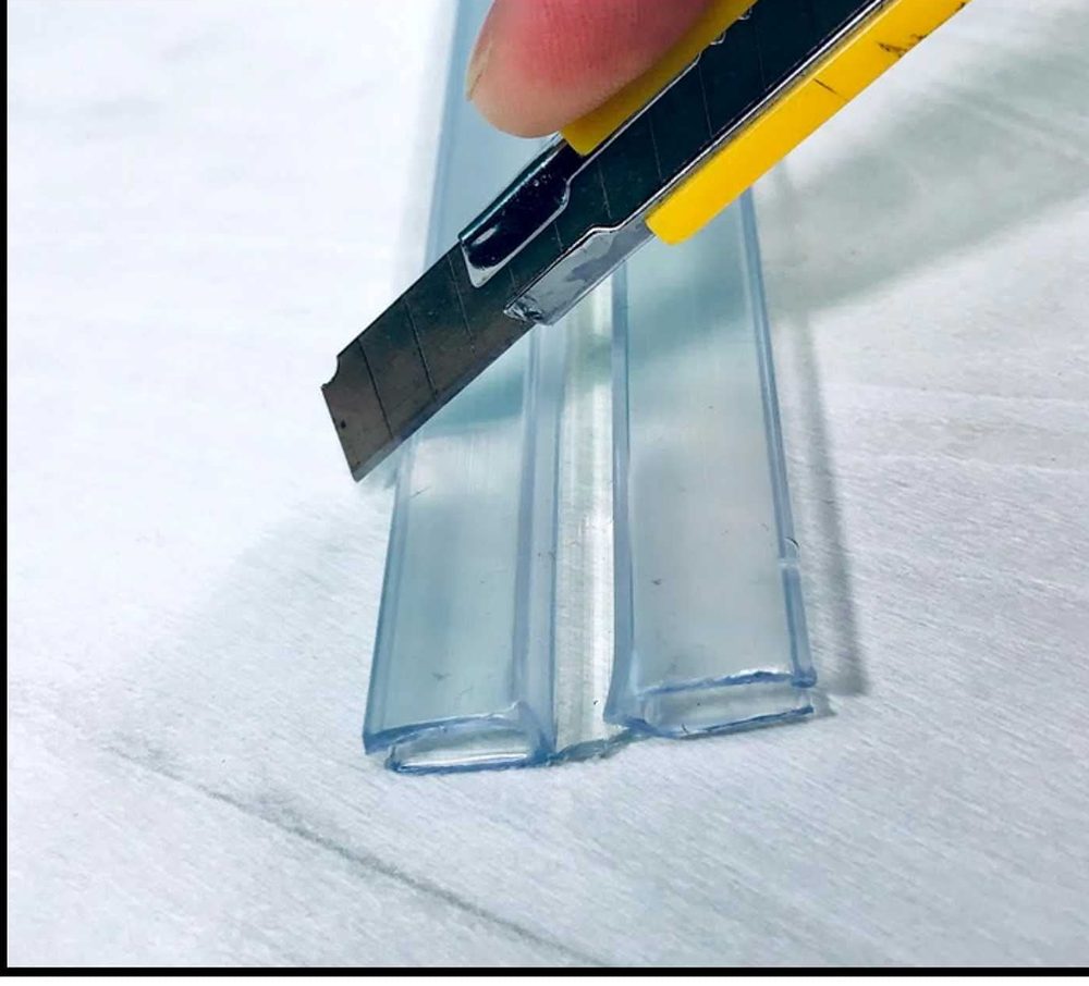 A utility knife trimming a clear PVC hinge to length