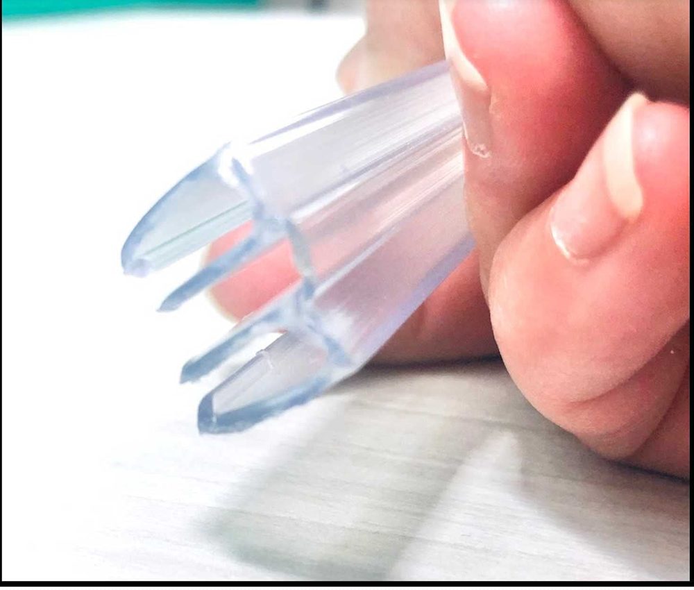 Fingers bending a clear PVC hinge to show its flexibility