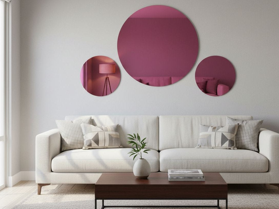 Three round rose gold mirror acrylic discs on a living room wall above a sofa