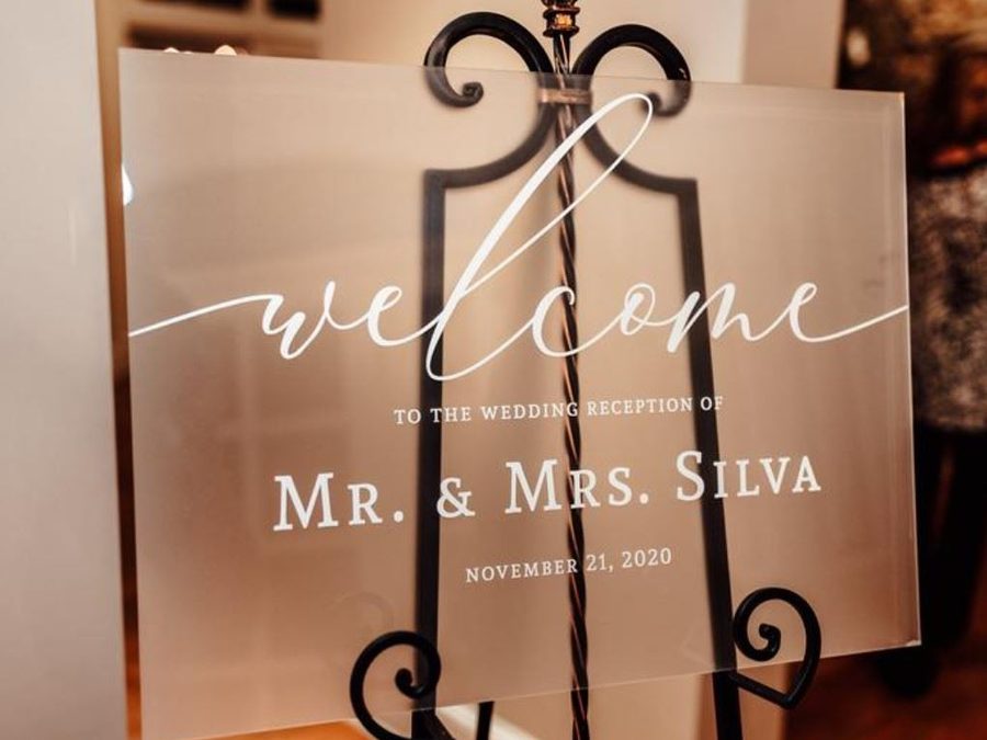 A frosted acrylic wedding welcome sign on an easel