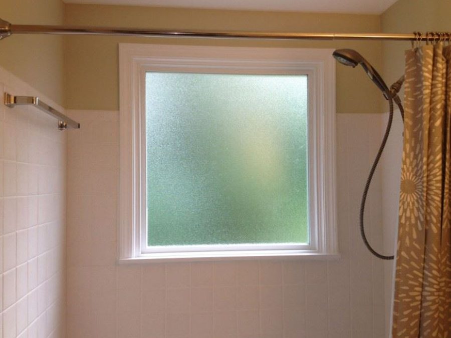 A frosted acrylic panel in a bathroom window above a bathtub